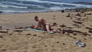 Fille qui bronze seins nus se fait baiser à la plage sur le sable, Naemyia